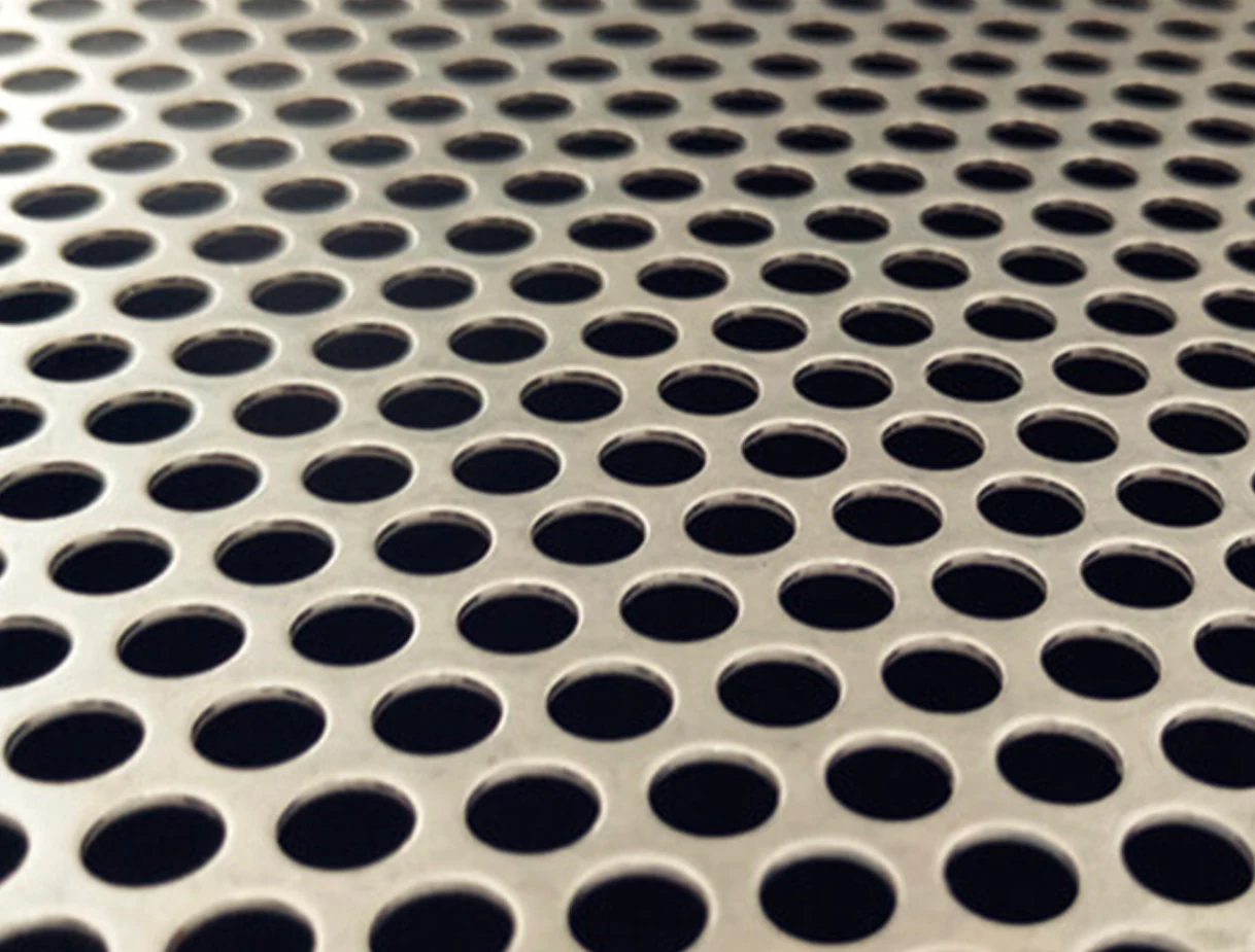 Close-up of round holes arranged in staggered rows in an unpainted perforated metal sheet